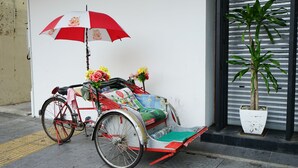 A bicycle with a red and white umbrella, a potted plant, and a flower arrangement. - Grand FC Hotel (George Town)