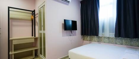 Ein Schlafzimmer mit Bett, Fernseher, Klimaanlage und Kleiderschrank.