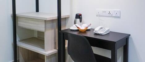 Habitación pequeña con escritorio, silla y lámpara colgante.