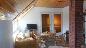 Una habitación acogedora con techo de madera, televisor, muebles de mimbre y chimenea de ladrillo.