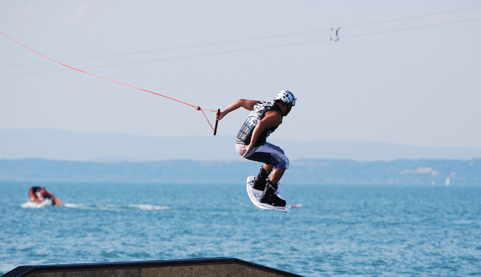 A person wakeboarding on a body of water with a clear sky in the background.