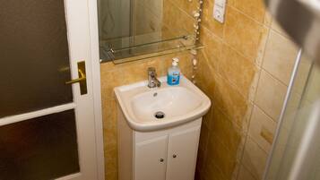 A bathroom with a white sink, a glass shelf above it, and a mirror.
