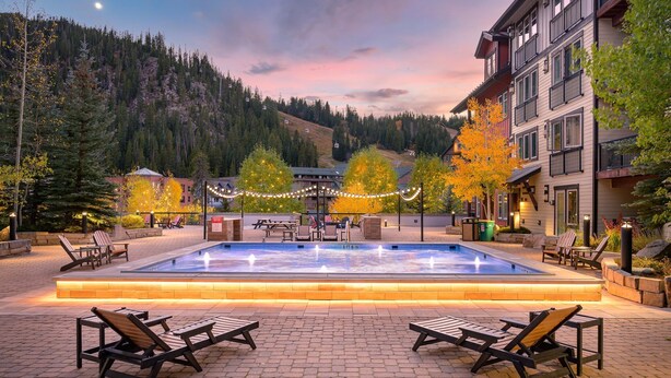 A pool area with lounge chairs, a water feature, and a view of a mountain.