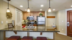 A modern kitchen with granite countertops, stainless steel appliances, and pendant lighting.