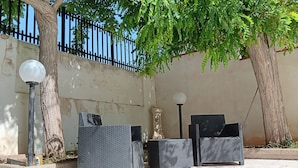 An outdoor seating area with two wicker chairs and a table, a lamp post, and a decorative pillar. - Villa at Sea (Avola)