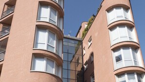 A multi-story building with a curved facade, large windows, and a central glass entrance. - New, Spacious, Bright, Elegant Loft Apartment With Balcony. Opposite the Hospital S. Orsola (Bologna)