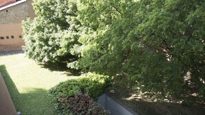 A courtyard with a brick wall, a grassy area, and a tree. - New, Spacious, Bright, Elegant Loft Apartment With Balcony. Opposite the Hospital S. Orsola (Bologna)