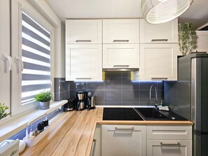 A modern kitchen with white cabinets, a black stove top, and a stainless steel refrigerator. - Paderewskiego (PD09) - PD09 (Swinoujscie)