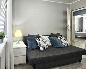 A bedroom with a bed, a bedside table with a lamp, and a potted plant. - Paderewskiego (PD09) - PD09 (Swinoujscie)