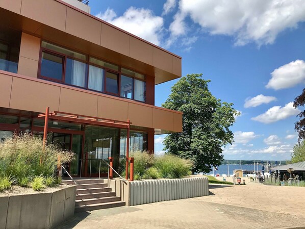 A modern building with a flat roof, large windows, and a staircase leading to the entrance. - Apartment Auszeit, Germany (Glücksburg (Ostsee))