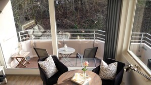 Un balcon moderne avec deux chaises noires, une petite table ronde et un pot de fleurs.