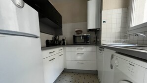 Una cuina compacta amb nevera, microones i rentavaixelles.