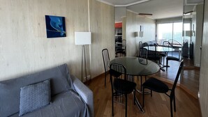 Habitació d'hotel moderna amb zona de menjador, un sofà i una finestra gran que ofereix vistes.
