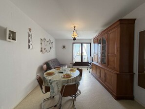 Un coin repas comprenant une table ronde, des chaises, un buffet et un luminaire au plafond.