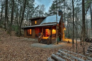 A cabin with a porch, a chimney, and a metal roof in a forest. - Lazy Lake | Cherry Log, GA (Cherry Log)