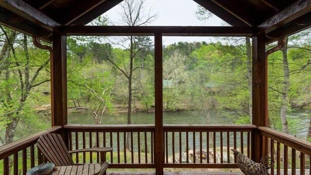 A wooden deck with a view of a forest and a river. - Casa Del Rio | Ellijay, GA (Ellijay)