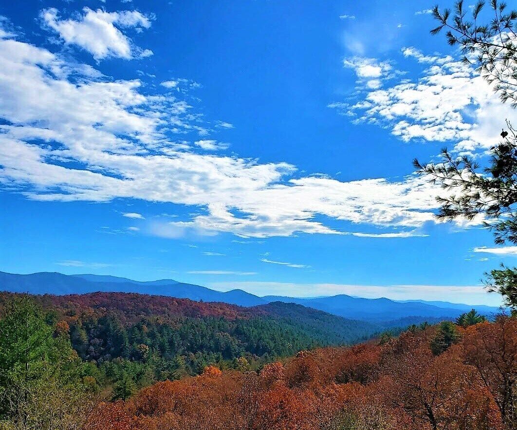 A mountainous landscape with autumn foliage, clear skies, and distant mountains.