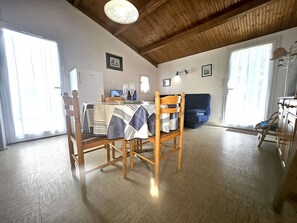 A dining area with a table set for four, a wooden dining chair, a sofa, and a cabinet.