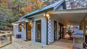A cabin with a covered porch, a grill, and a wooden deck. - Hemlock Creek | Cherry Log, GA (Cherry Log)