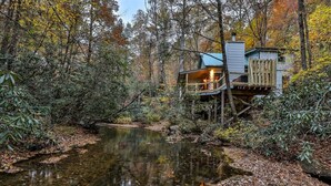 A cabin with a deck overlooking a stream, surrounded by dense forest. - Hemlock Creek | Cherry Log, GA (Cherry Log)
