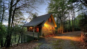 Eine Hütte mit Veranda, umgeben von Bäumen.