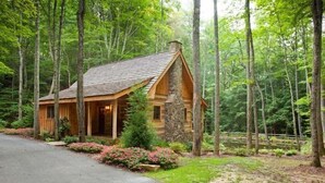 Eine Blockhütte mit einem Steinkamin, umgeben von einem Wald.