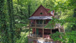 Een chalet met balkon, omgeven door dicht bos.
