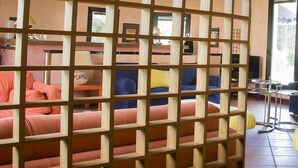 A living room with a wooden partition, a blue sofa, a yellow armchair, and a pink sofa. - Aliajazz hotel (Castrovillari)