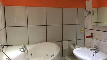 Un baño con bañera, lavamanos y espejo.
