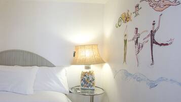 A bedroom with a bed, a bedside lamp, and a wall mural.