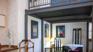 A room with a wooden desk, a chair, a small table with a lace tablecloth, and a balcony with a railing. - Aliajazz hotel (Castrovillari)