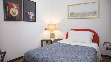 Une chambre d’hôtel avec un lit, une table de chevet, une lampe et deux tableaux encadrés au mur.