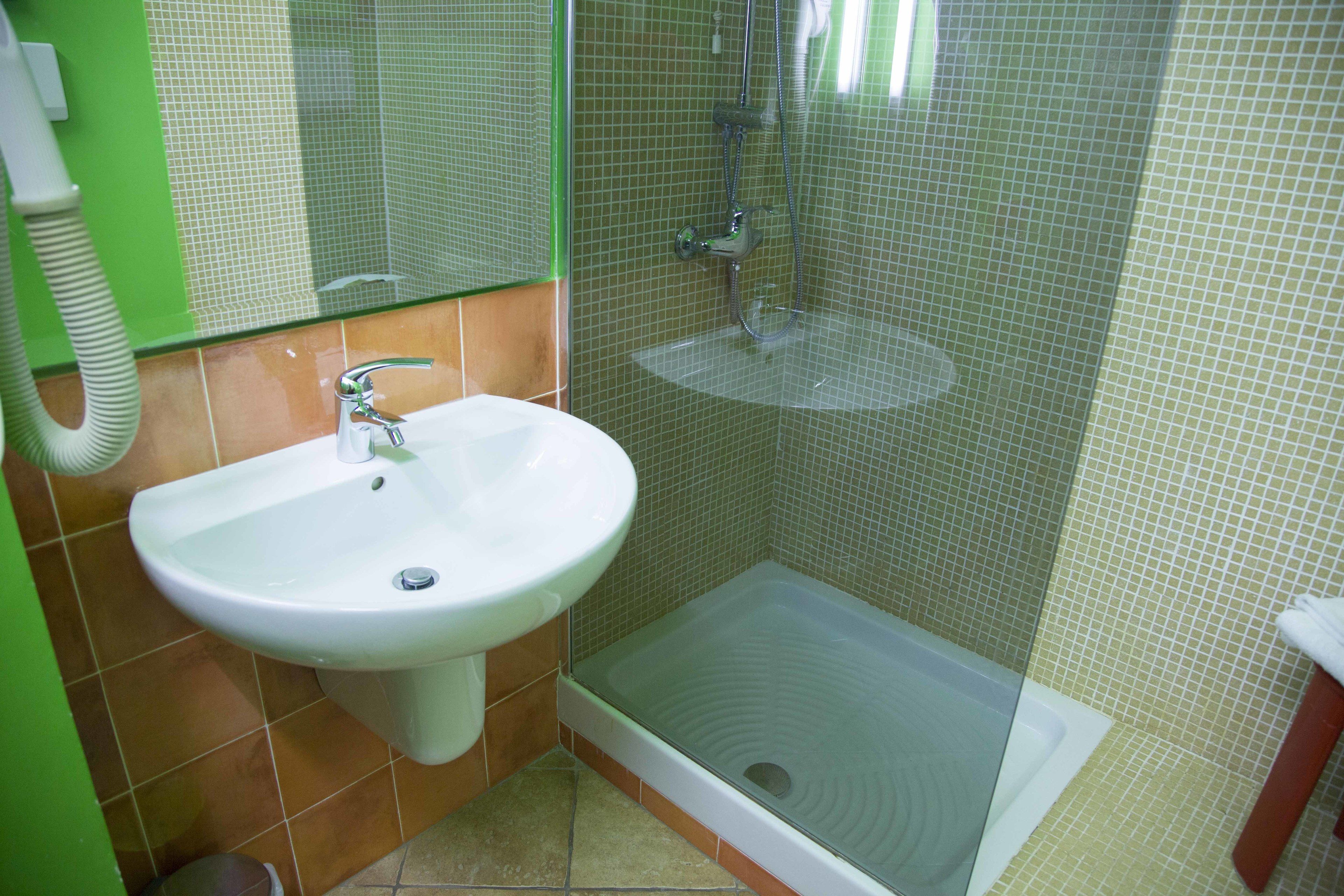 Un baño con lavamanos blanco, cabina de ducha e inodoro.