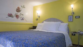 Ein Hotelzimmer mit Bett, Nachttisch, Lampe und Wandbild.
