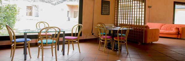 A room with a dining area featuring a table and chairs, a sofa, and a view through a window. - Aliajazz hotel (Castrovillari)