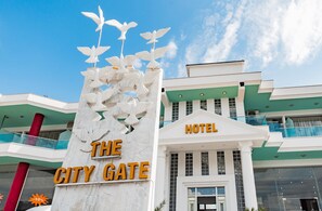 A hotel named "The City Gate" with a prominent sign featuring white birds and a 10% discount symbol. - The City Gate Hotel (Sarandë)