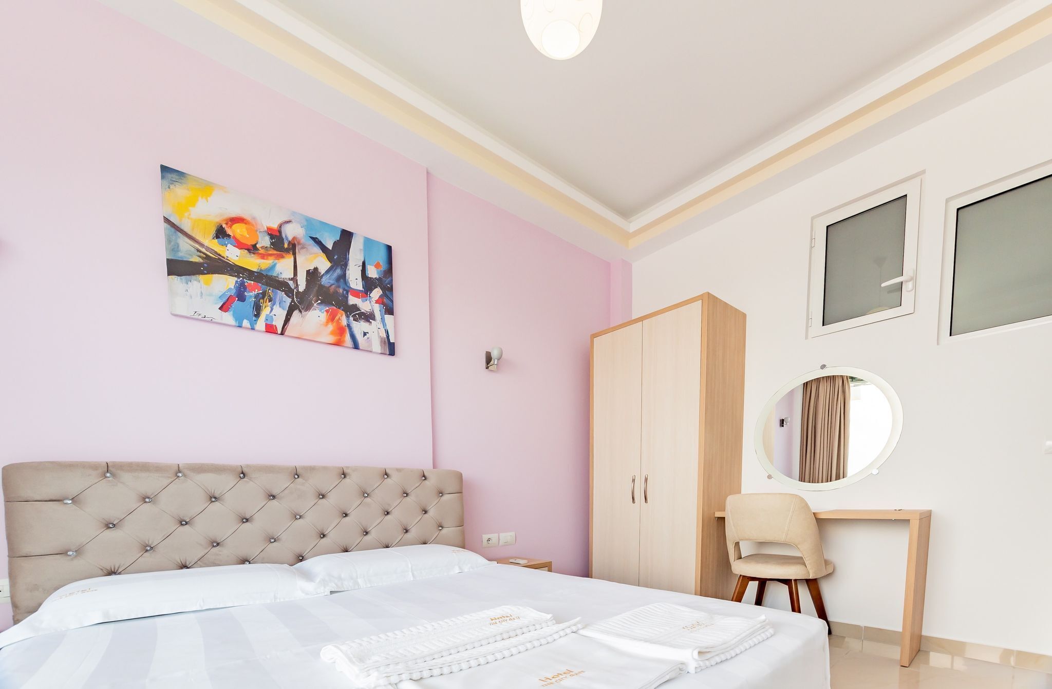 Una camera da letto con un letto, un armadio, una scrivania e un quadro appeso al muro.