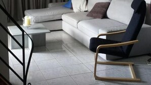 A modern living room with a white sofa, a black chair, and a glass coffee table. - Marysplacestalis (Hersonissos)