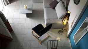 A modern living room with a grey sofa, a black chair, a small white table with a candle, and a floor lamp. - Marysplacestalis (Hersonissos)