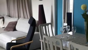 A living room with a sofa, a dining table with chairs, a clock on the wall, and a window with curtains. - Marysplacestalis (Hersonissos)