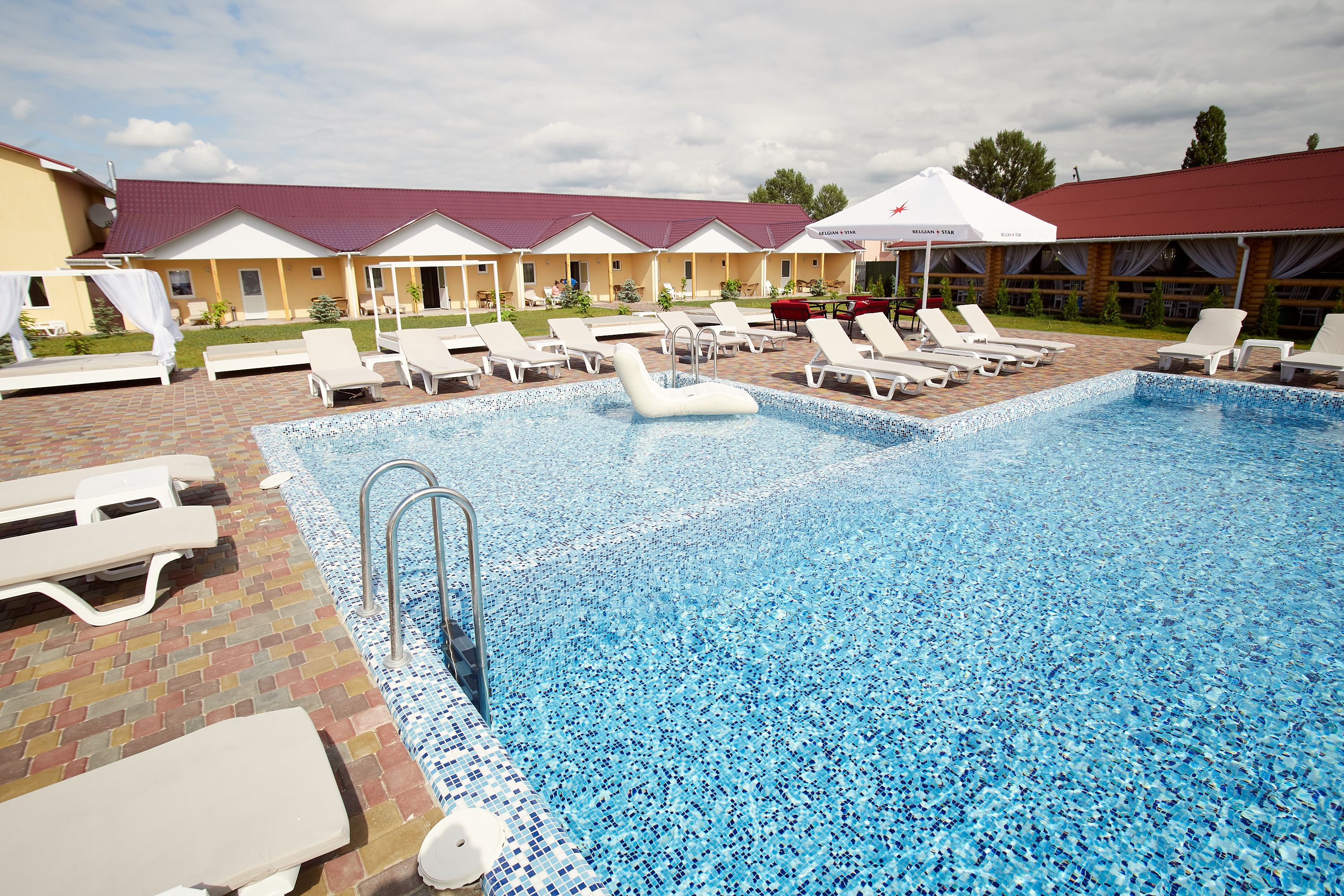 A swimming pool with lounge chairs and a covered area with umbrellas.