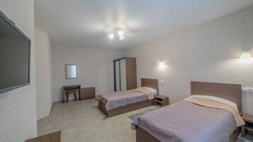 A hotel room with two beds, a desk, a mirror, and a TV.