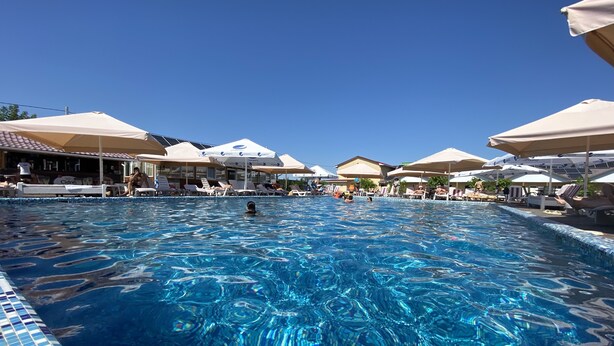 Una piscina con agua cristalina, rodeada de sillones de baño y sombrillas.