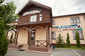 A building with a sign reading "Restoran" and "Aborik." It features a wooden facade with a balcony and steps leading to the entrance. - Rayskiy Dvorik (Pohreby)