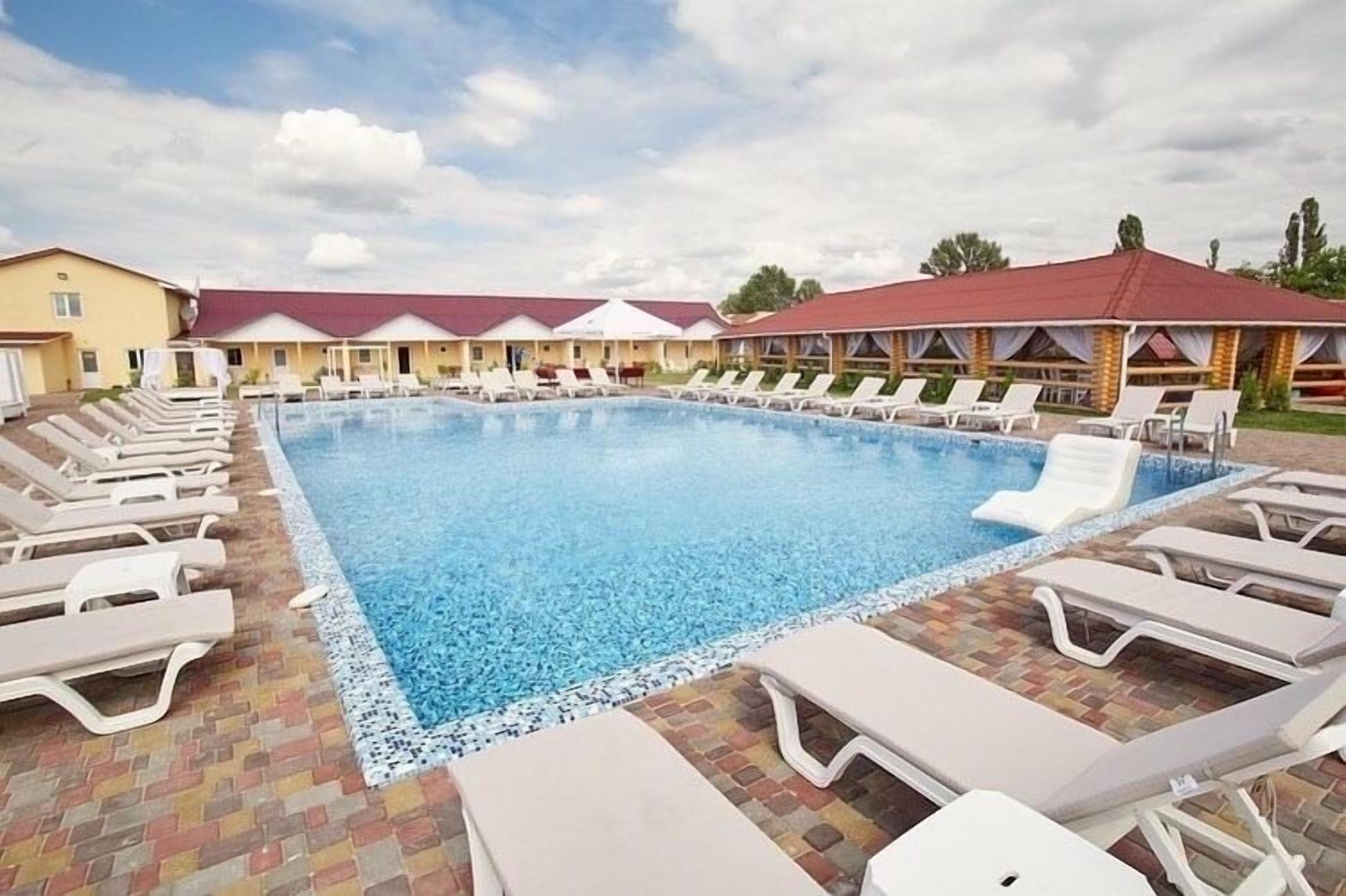 A swimming pool with lounge chairs and a row of buildings in the background.