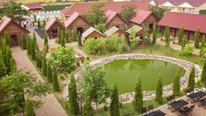 Un complejo turístico con cabañas de madera, piscina y un estanque circular.