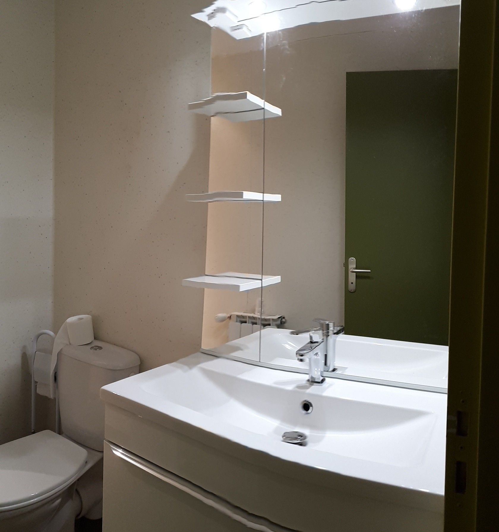 A bathroom with a white sink, a mirror, and a toilet.