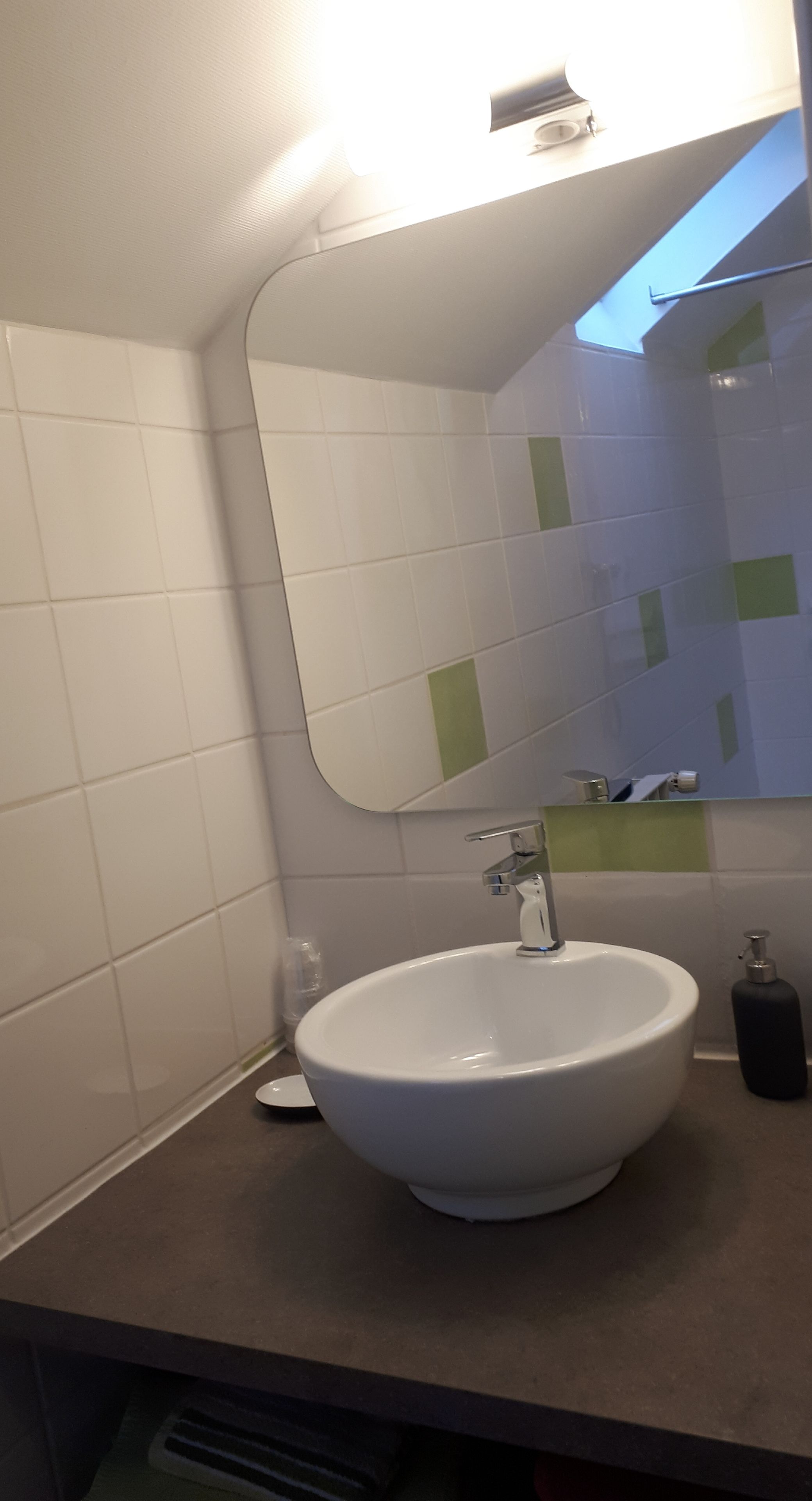 A bathroom with a white sink, a mirror, and a towel dispenser.