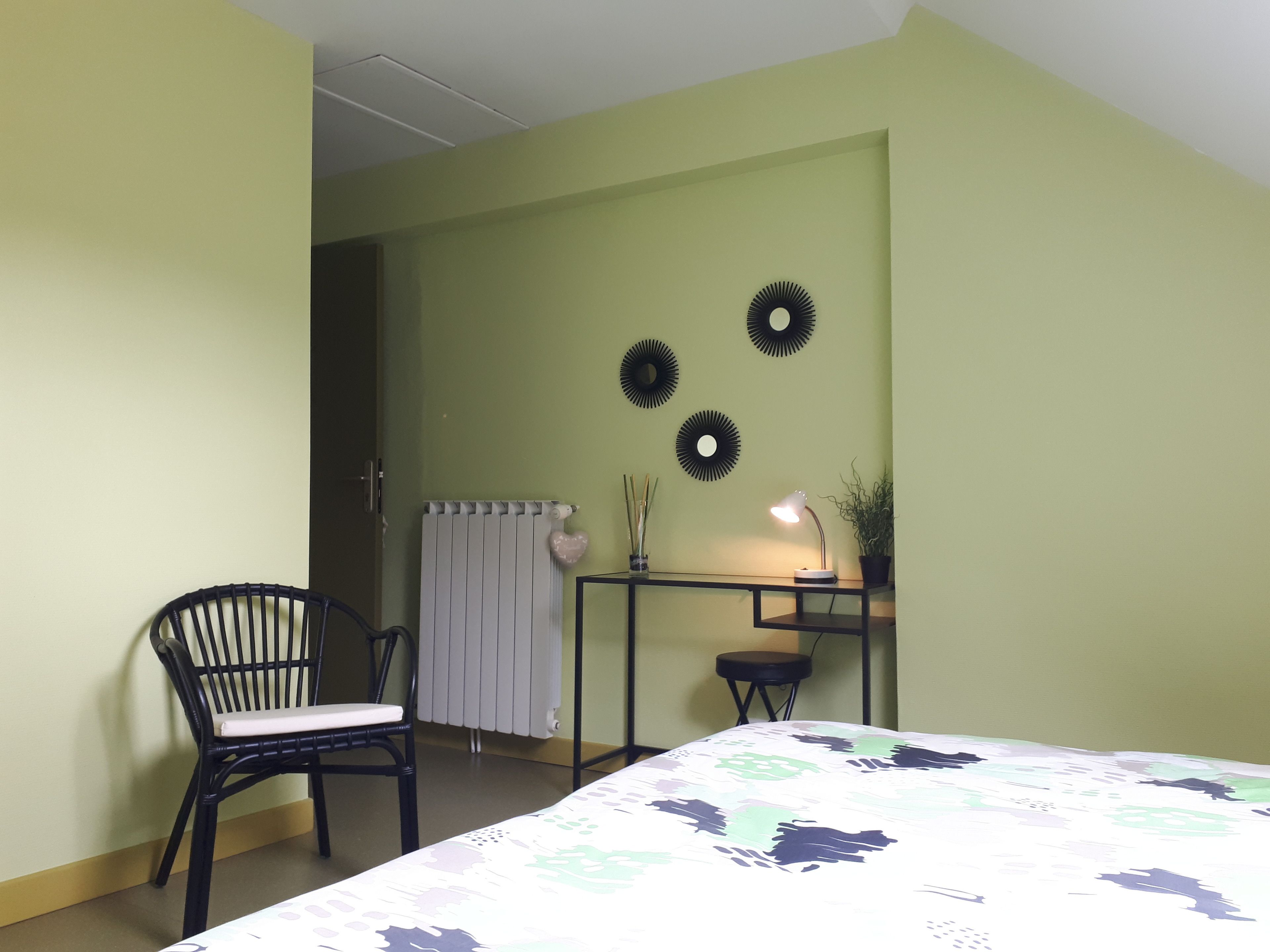 Une pièce comprenant un lit, un bureau avec une lampe, une chaise et des éléments décoratifs sur les murs.