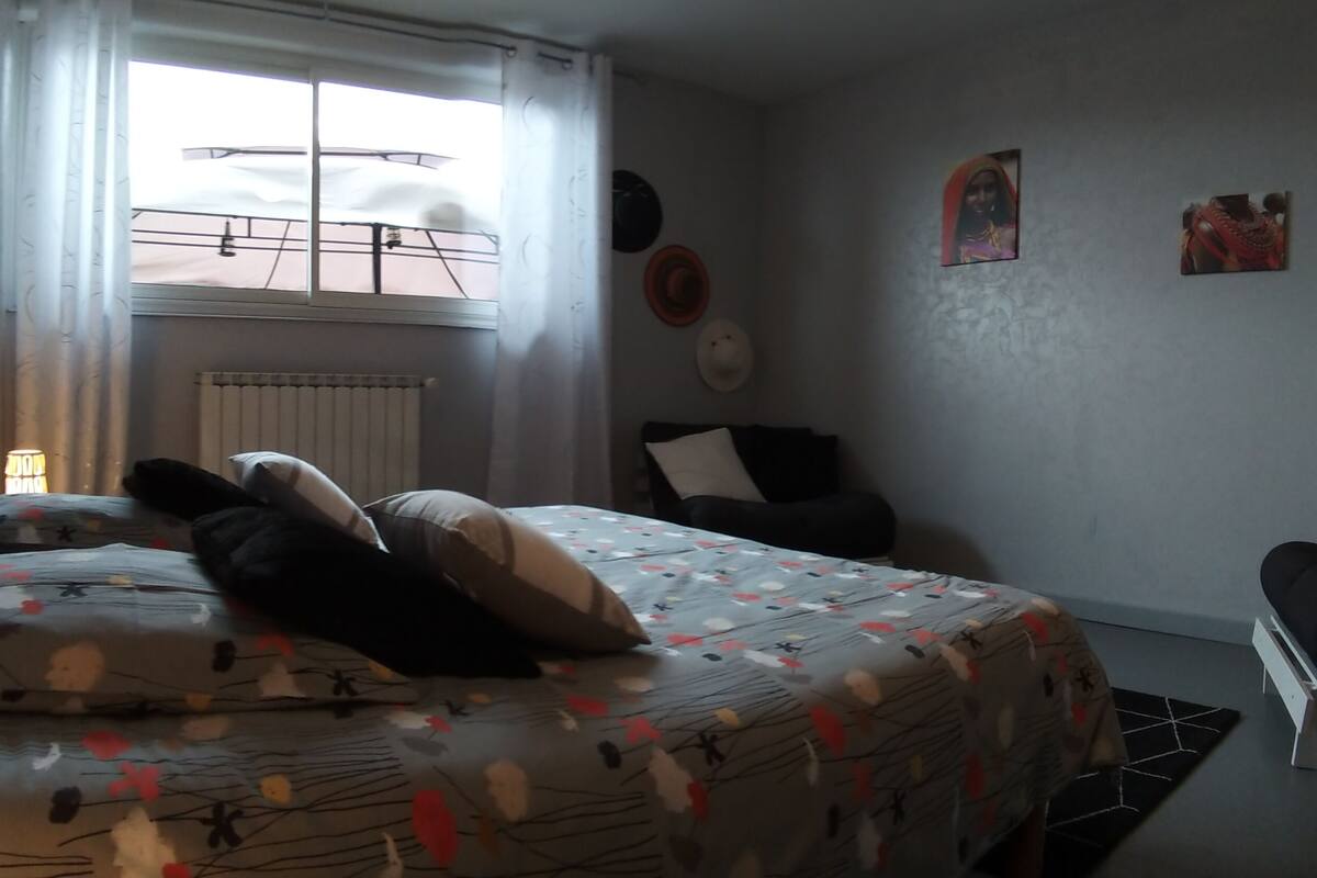 A bedroom with a bed, a chair, a radiator, and a window.